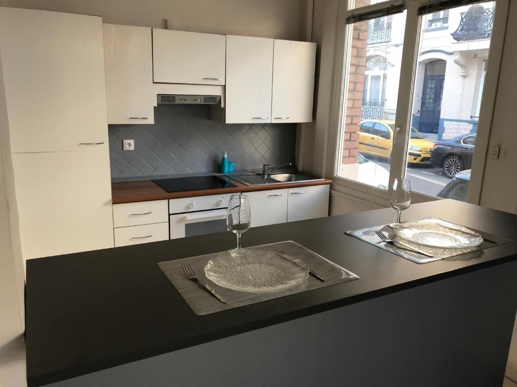 a kitchen with white cabinets and a black counter top at Studio 50m Plage in Dunkerque