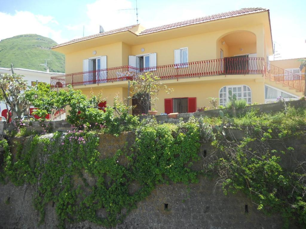 una casa gialla con balconi in cima a un muro di Appartamenti La Balestra a Ischia