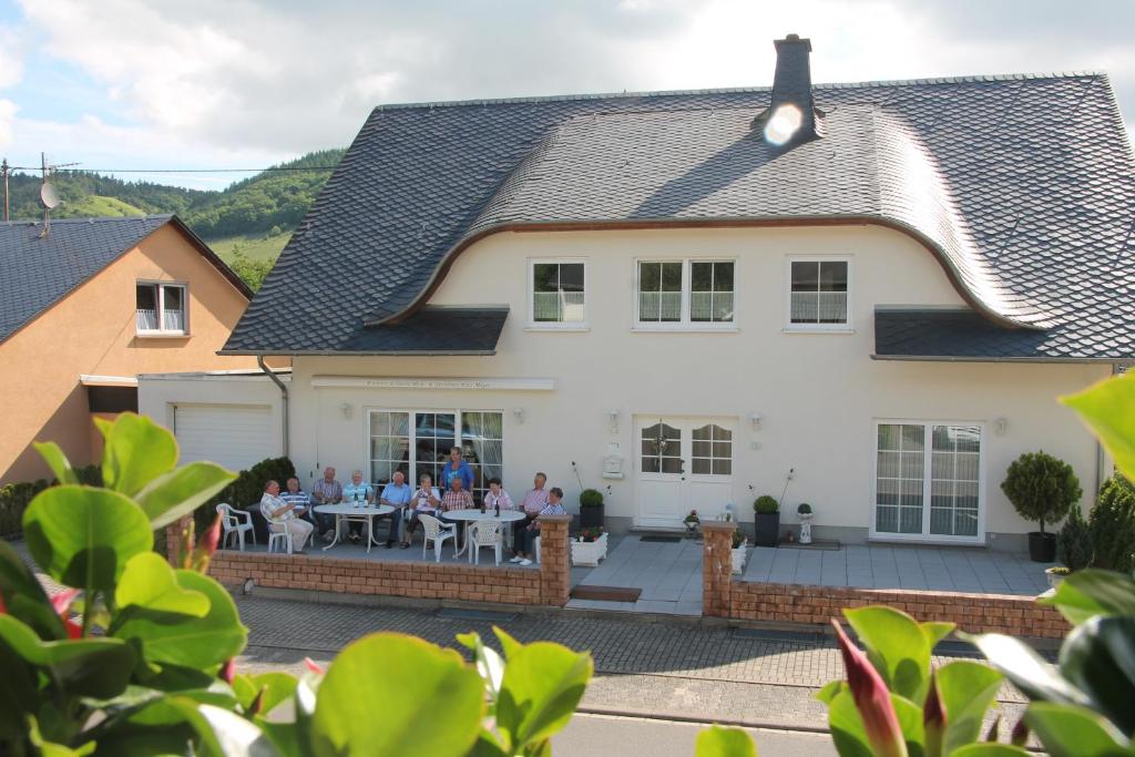 a group of people sitting at tables outside of a house at Wein- und Gästehaus Binz-Meyer in Lieser