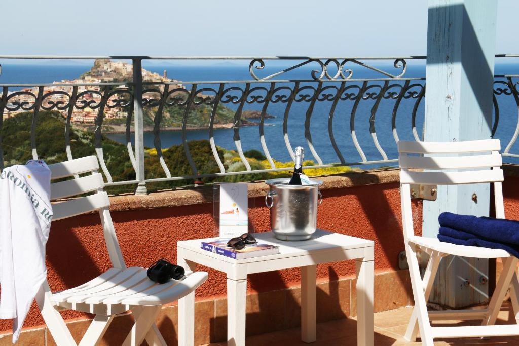 a table and chairs on a balcony with a view of the ocean at Sardinia Re - Attico Baja Ostina in Castelsardo