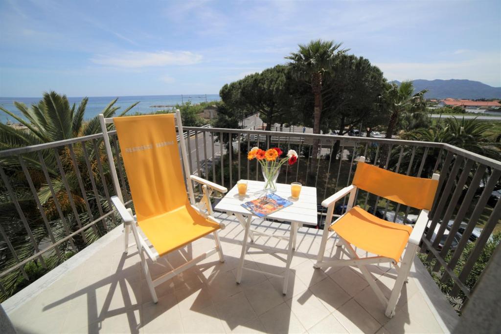 dwa krzesła i stół z kwiatami na balkonie w obiekcie Residence Sabrina w mieście Ceriale