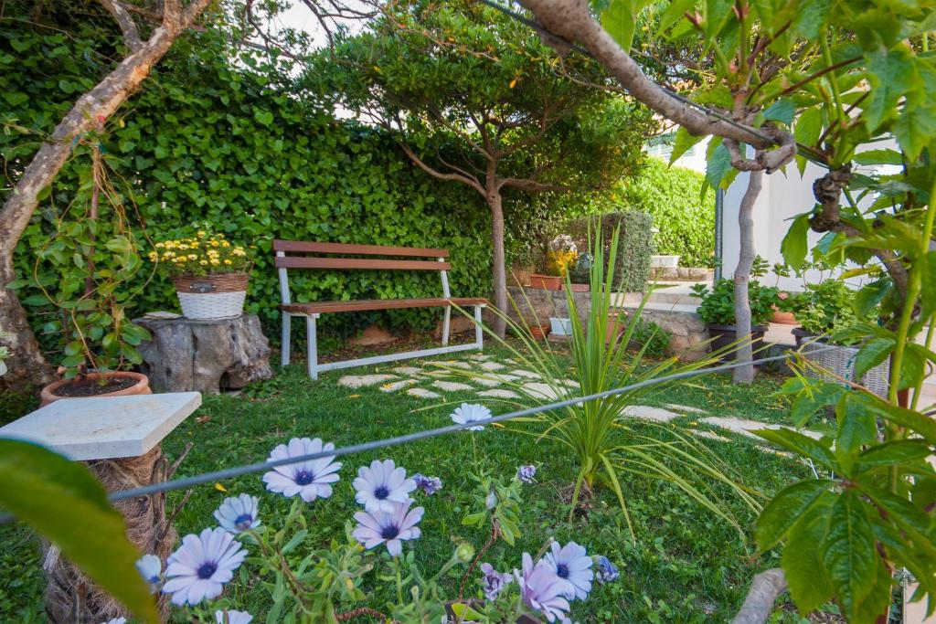 eine Holzbank in einem Garten mit Blumen in der Unterkunft Apartment Petra in Brodarica