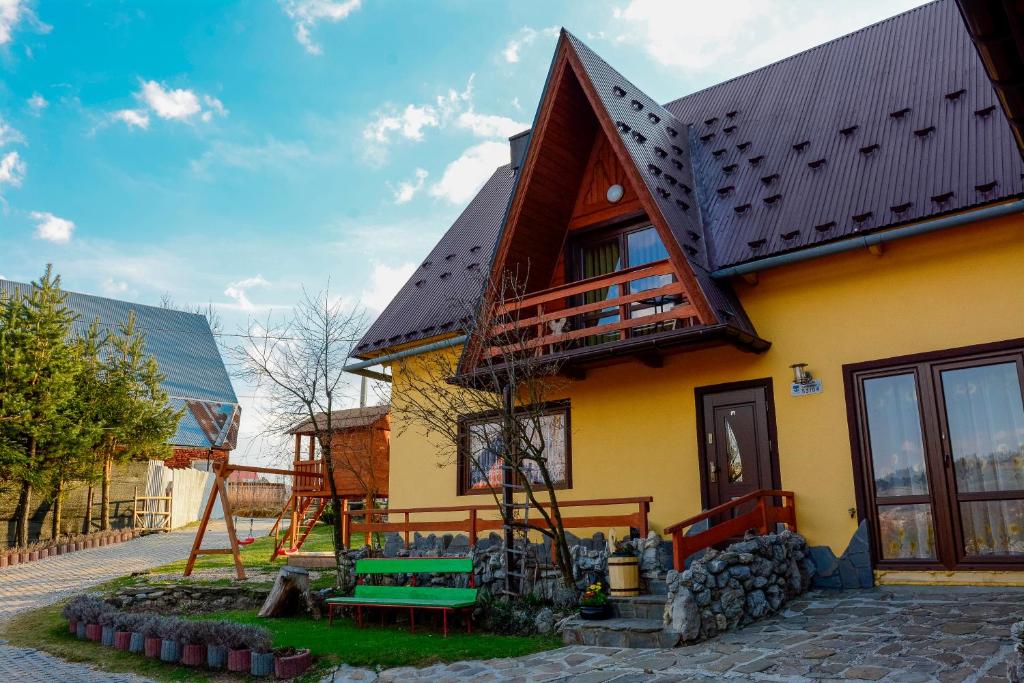 a yellow house with a wooden roof and a playground at Domek Koniec Świata in Dzianisz