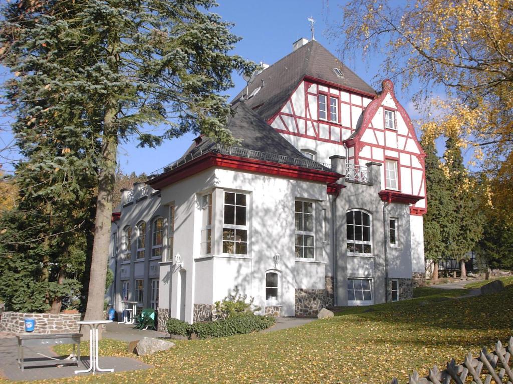 a large white and red house with a tree at Waldhotel Forsthaus Remstecken in Koblenz