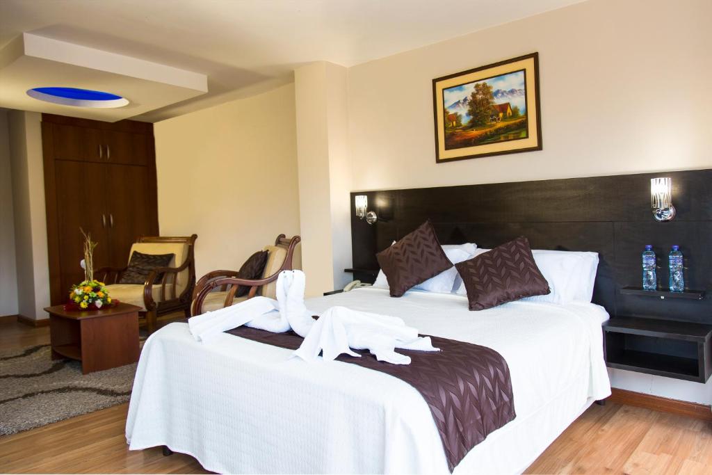 a hotel room with a large bed with white sheets at Hotel Versailles in Ambato