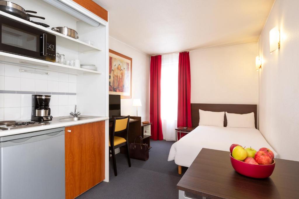 a hotel room with a bed and a bowl of fruit on a table at Aparthotel Adagio Access La Défense - Léonard De Vinci in Courbevoie