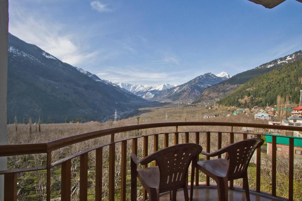 2 Stühle auf einem Balkon mit Bergblick in der Unterkunft Sarthak Resorts-Reside in Nature with Best View, 9 kms from Mall Road Manali in Manali