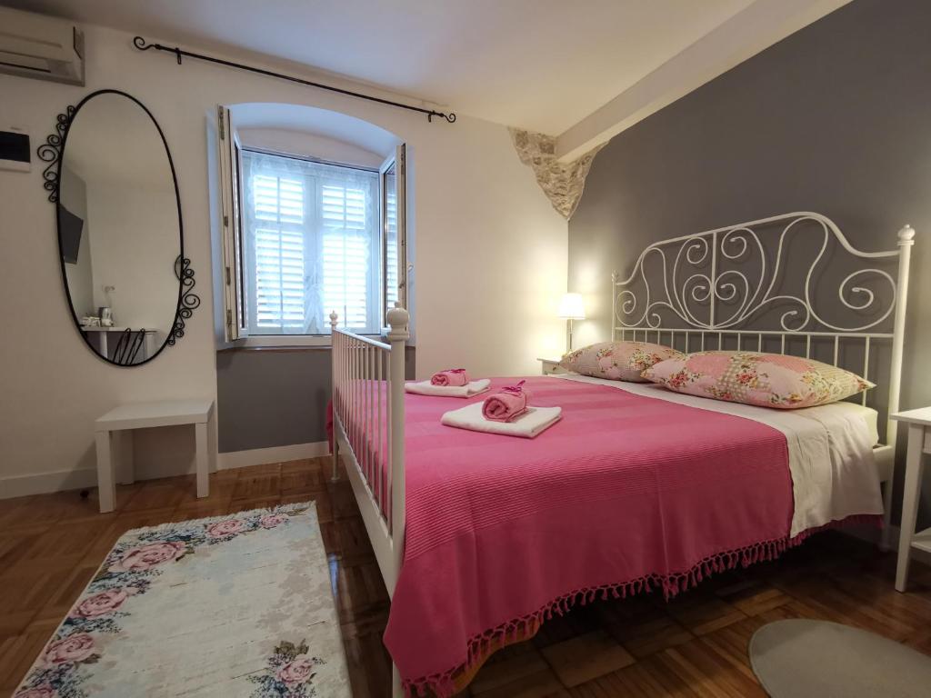 a bedroom with a bed with a pink blanket and a mirror at Palace Inn Rooms in Split