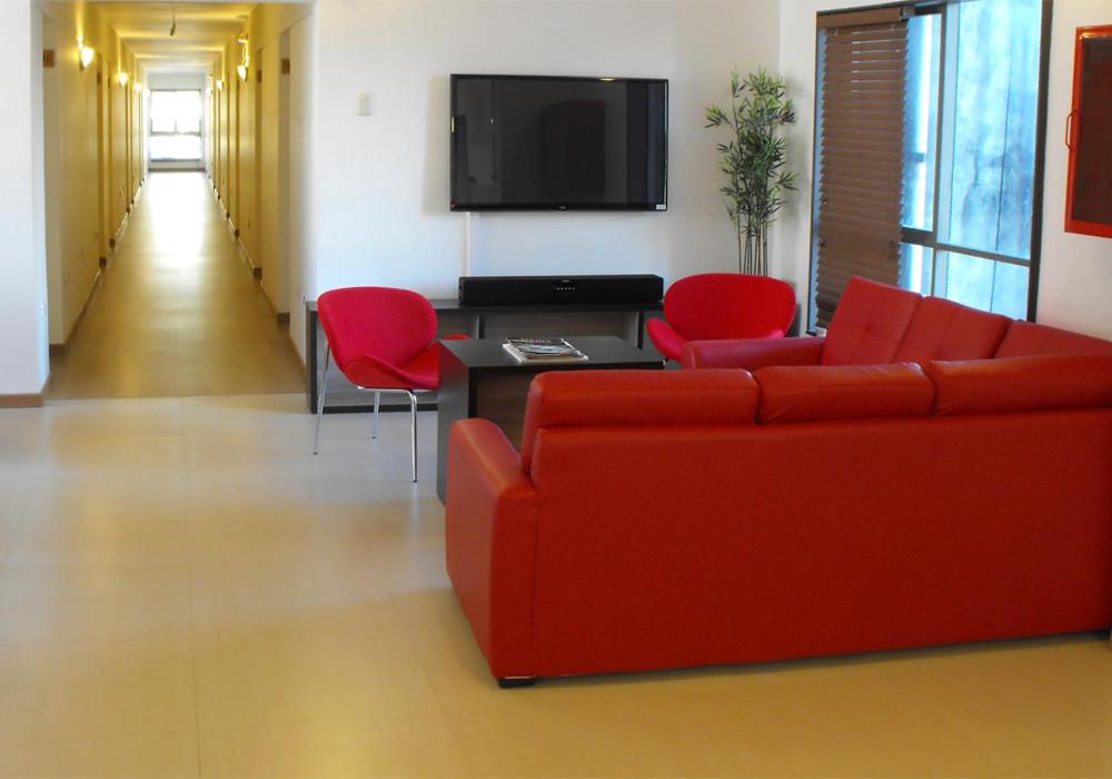 a living room with a red couch and red chairs at Hotel Romano in Concepción