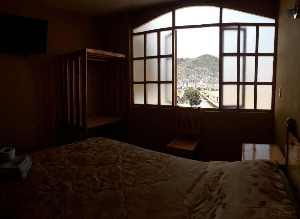 een slaapkamer met een bed en een groot raam bij Hostal Cactus in Cuzco