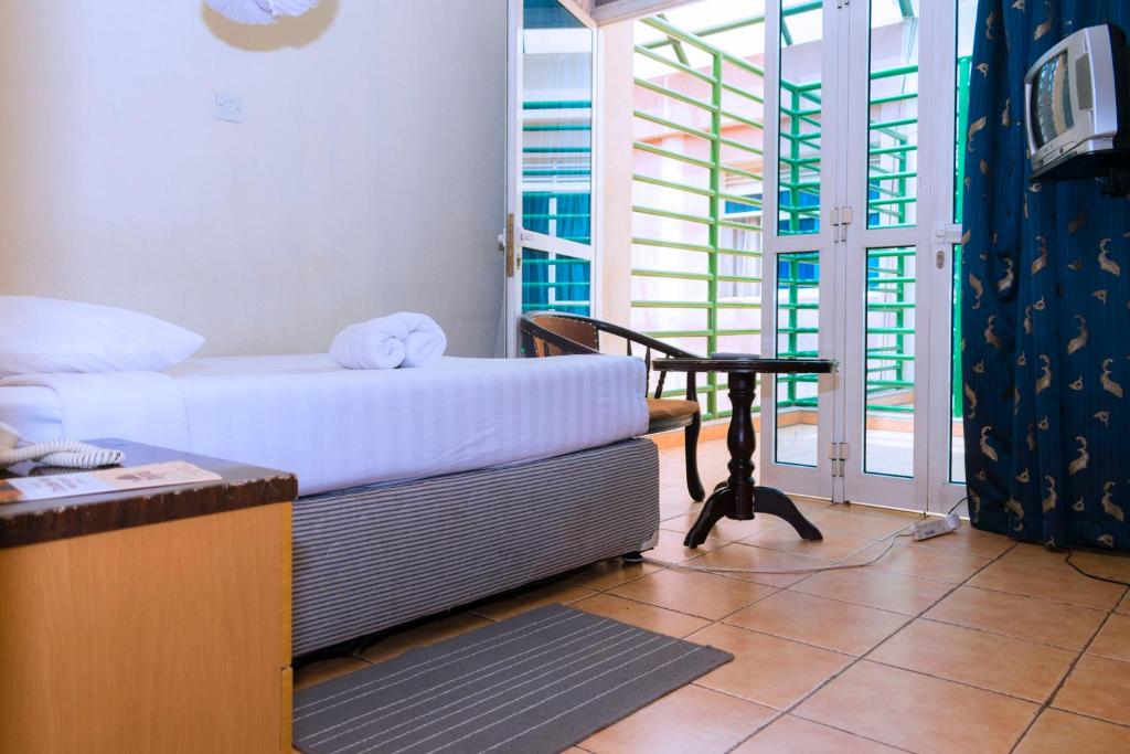 a room with a bed and a table and a window at Aponye Hotel Kampala in Kampala
