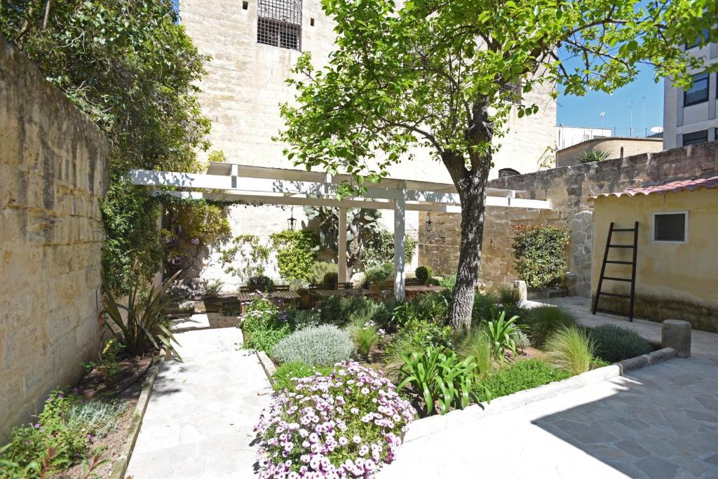 レッチェにあるIl Giardino Di Benedettaの建物前の木と花の庭園