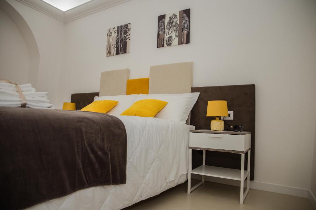 1 dormitorio con 1 cama con almohadas amarillas y mesa auxiliar en LA CIVITA B&B, en Gravina in Puglia