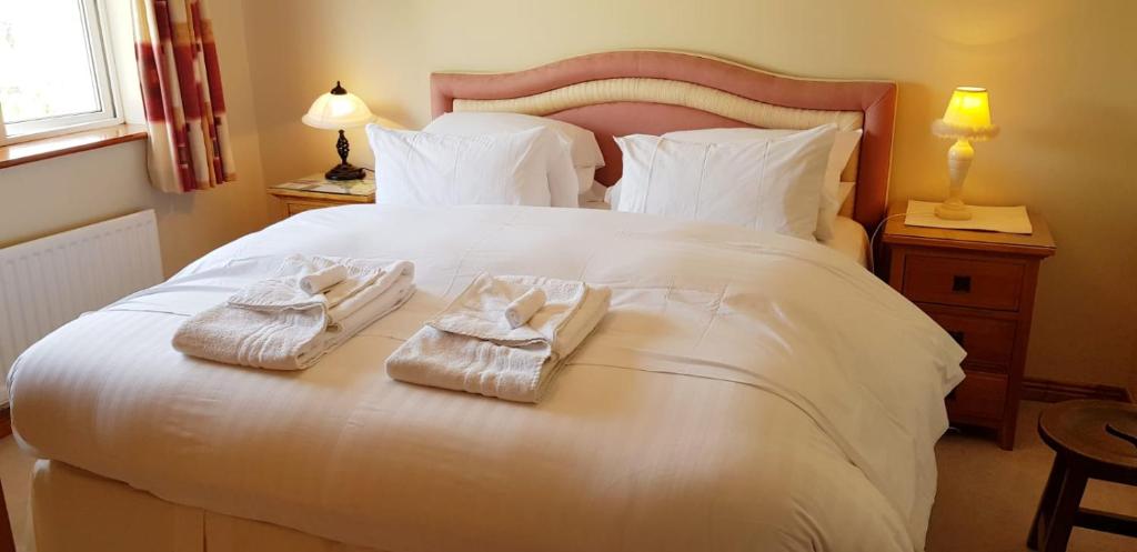 um quarto com uma cama branca e toalhas em Claremount House B&B em Galway