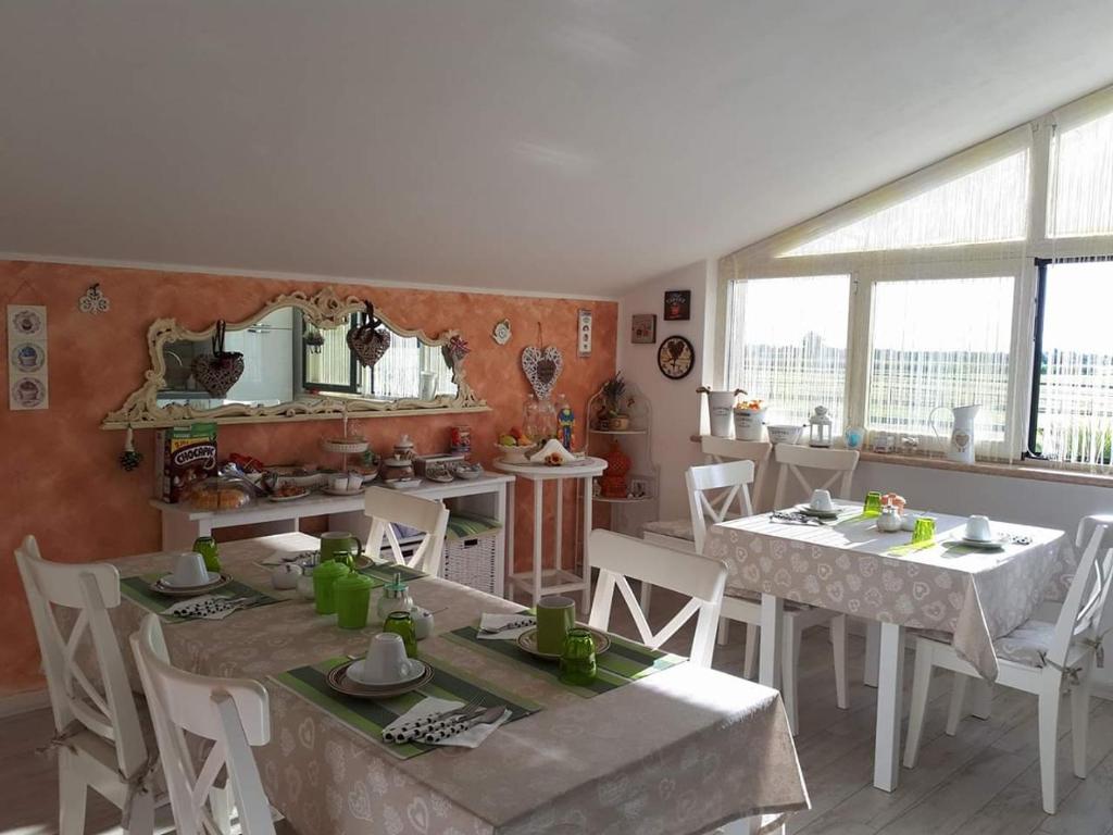 uma sala de jantar com duas mesas e cadeiras brancas em B&B A casa di Eleonora em Villafranca di Verona