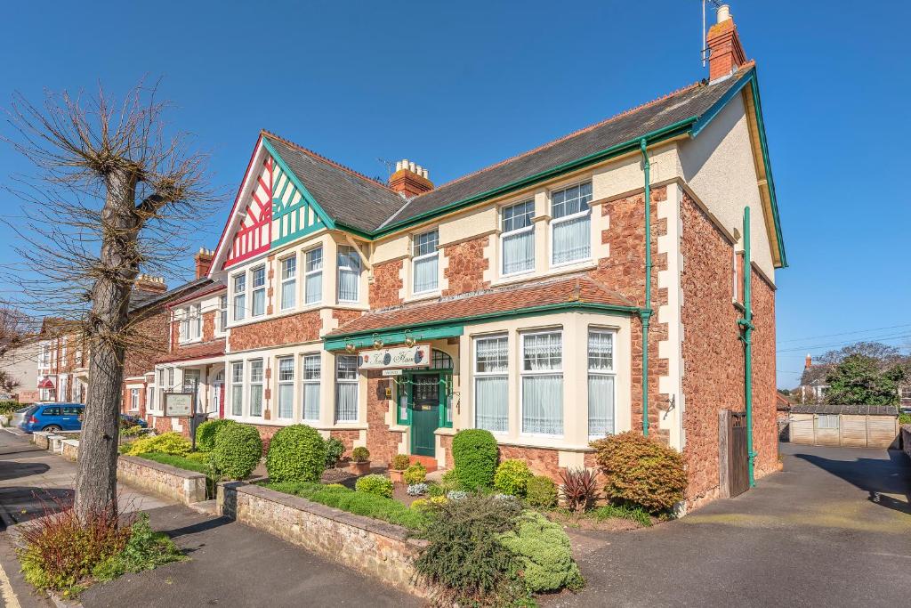 una casa de ladrillo rojo con un árbol delante en Kenella House, en Minehead