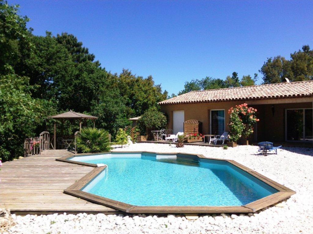 uma piscina com um deque de madeira ao lado de uma casa em La Mouchelière em La Garde-Freinet