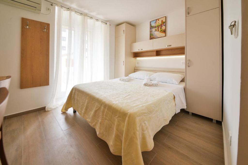 a bedroom with a bed with white sheets and a window at Apartmani Ljubo Rafailovic 2 in Rafailovici