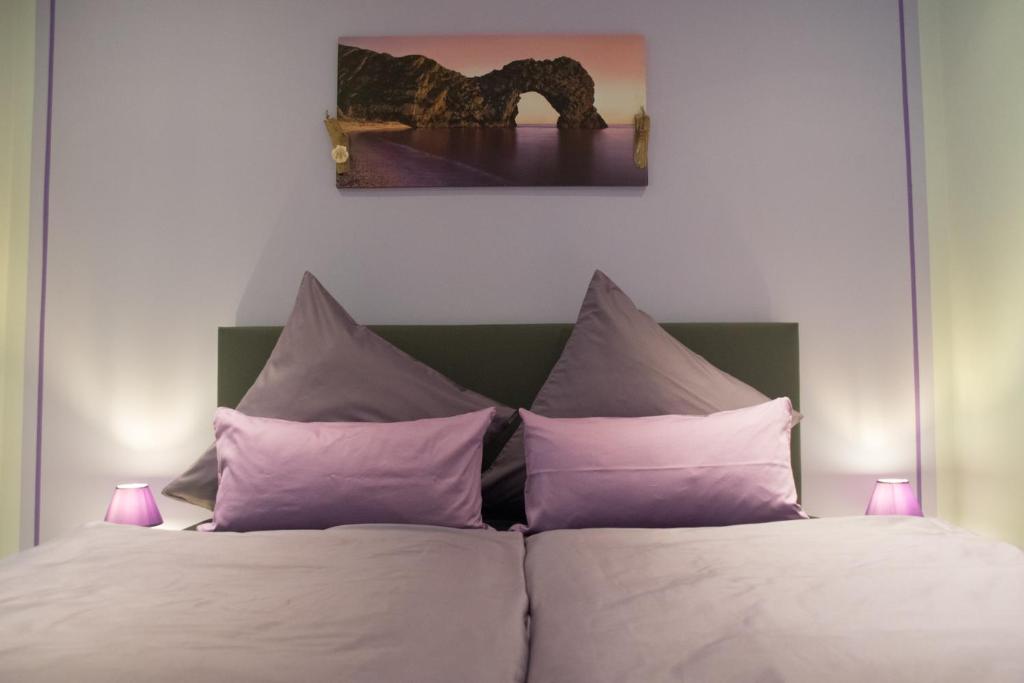 um quarto com uma cama com almofadas roxas em Zimmervermietung Hebenstreit em Bernburg