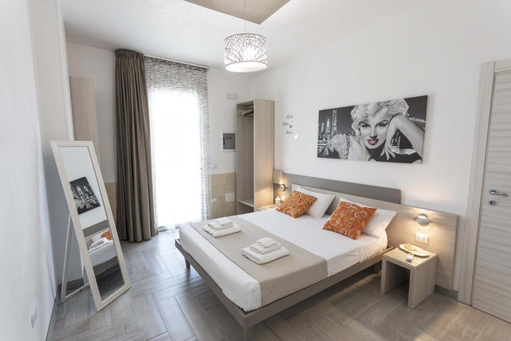 Habitación blanca con cama y espejo en Viva Vacanze en Porto Cesareo