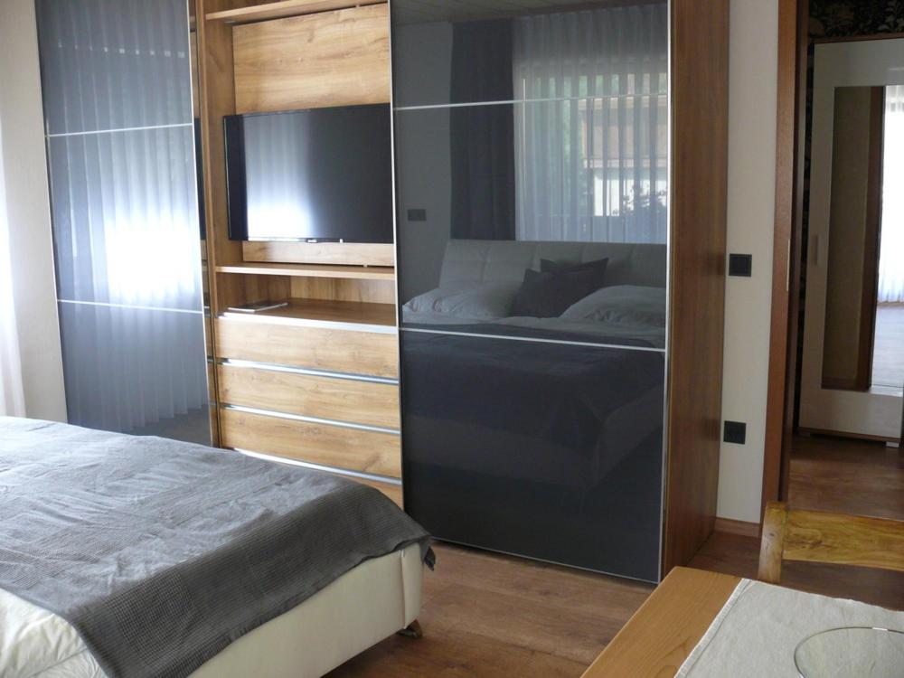 een slaapkamer met een bed en een flatscreen-tv bij Ferien Wohnung "Kaiser" mit Balkon und Garten in Offenhausen