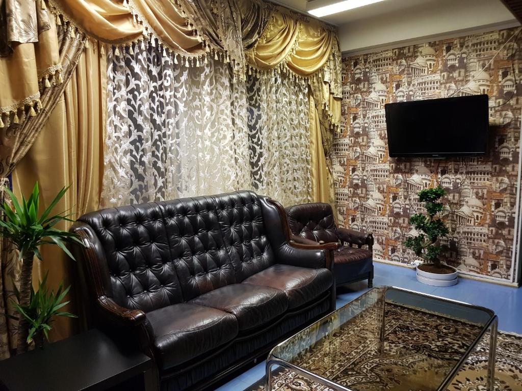 a living room with a leather couch and a television at Hotel Ilomantsi North Star in Ilomantsi