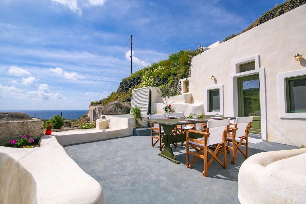 un patio con mesa, sillas y el océano en Agrilia secluded cave house en Thirasia