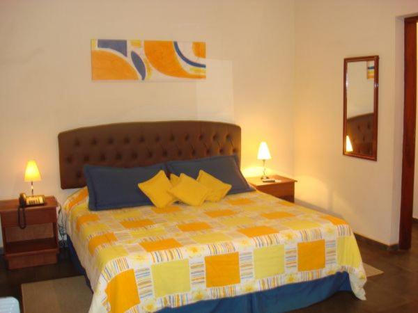 a bedroom with a bed with yellow and blue pillows at Hotel Fazenda Reviver in Araçoiaba da Serra