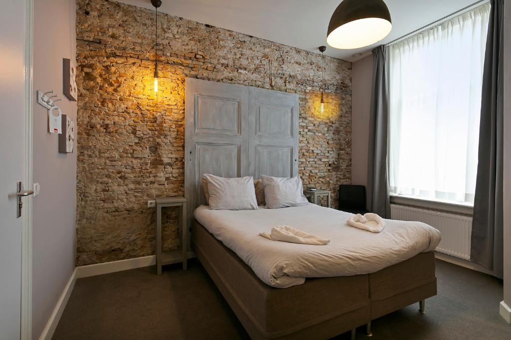 a bedroom with a bed with a brick wall at Hotel Heere in Raamsdonksveer