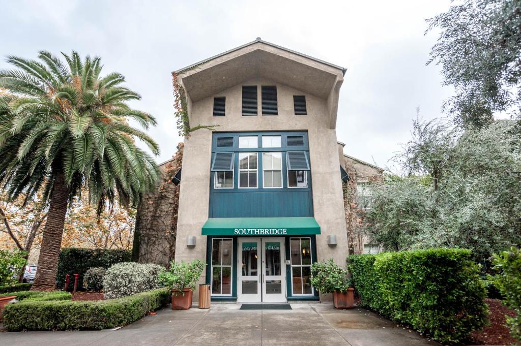 a building with a green awning and palm trees at Southbridge Napa Valley in St. Helena