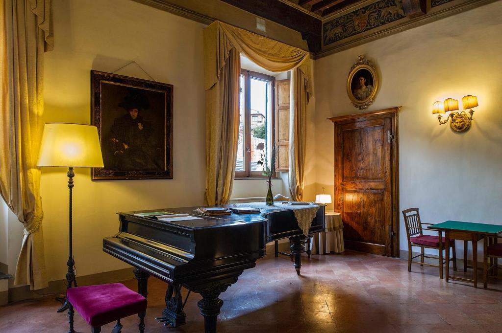 Zimmer mit einem Klavier, einem Tisch und einem Fenster in der Unterkunft Palazzo Ravizza in Siena