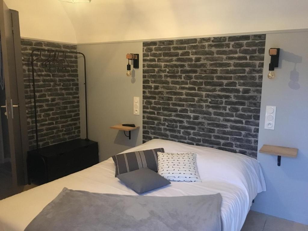 a bed in a room with a brick wall at La Pénate in Pluduno