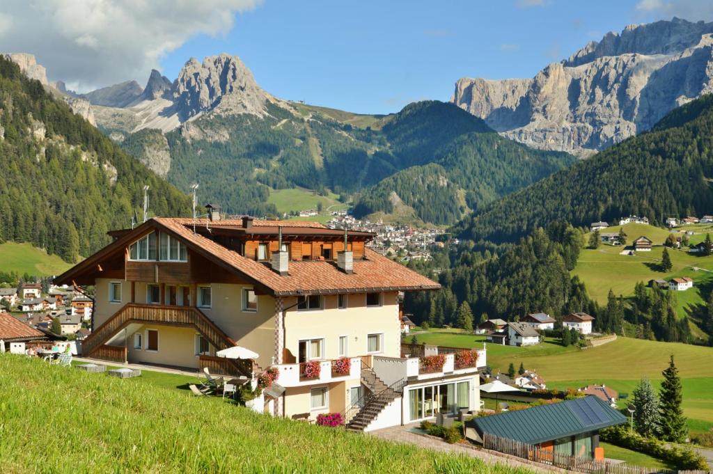 a house on a hill with mountains in the background at Apartments Etruska Gabriela in Santa Cristina Gherdëina