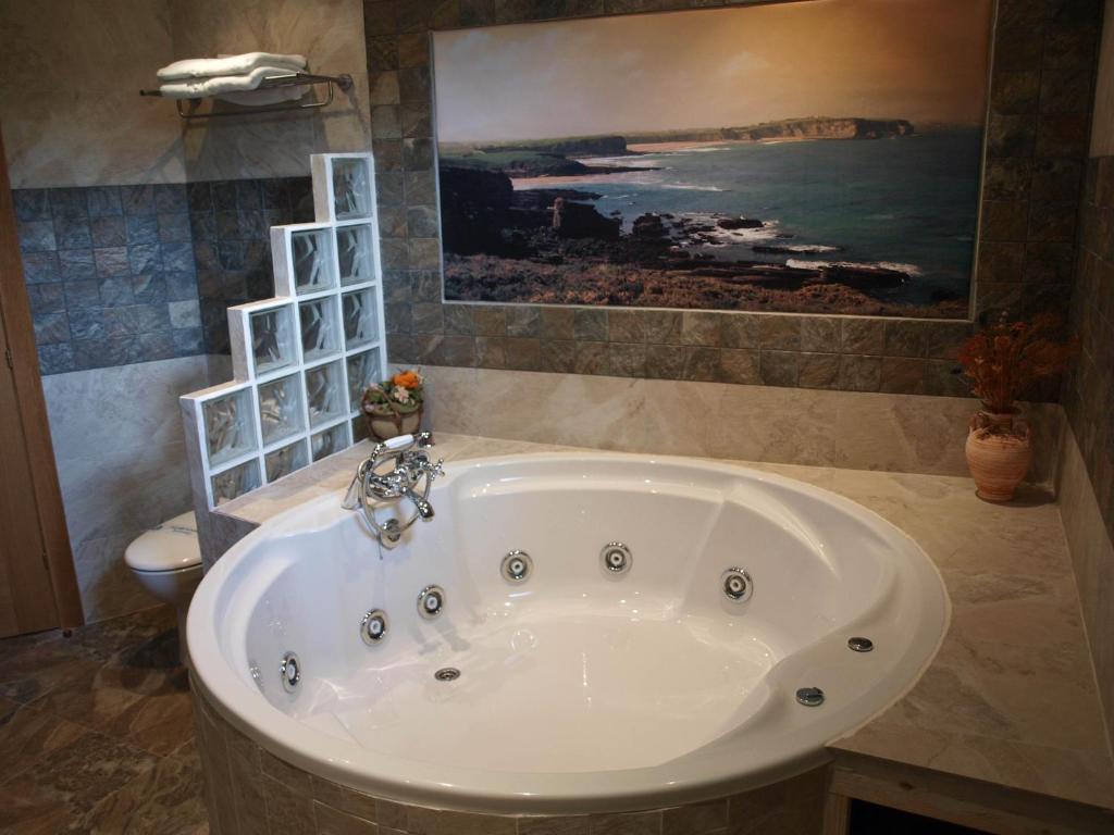 een badkuip in een badkamer met een schilderij aan de muur bij Hotel "Posada de Cantabria EL SOLAR" -Cenas típicas y Gintonic- Bar -Terraza panorámica in Galizano