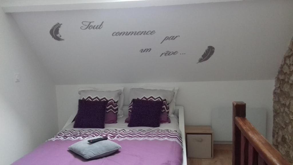 een slaapkamer met een bed met paarse lakens en woorden aan de muur bij La Reine des Plages in Hardelot-Plage