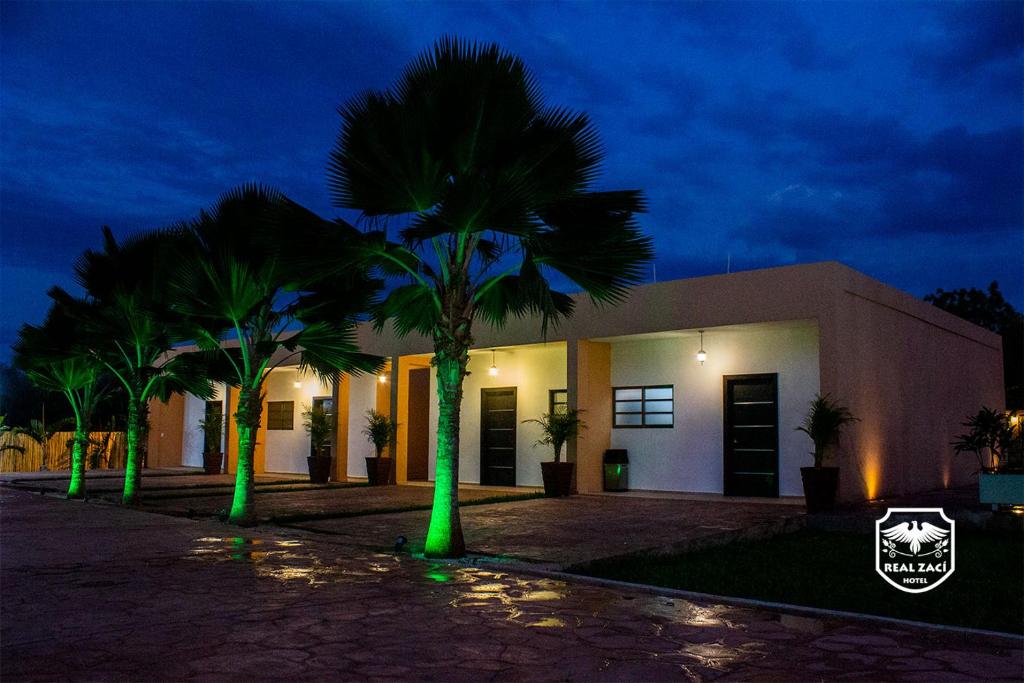 a building with palm trees in front of it at night at Hotel Real Zaci in Valladolid