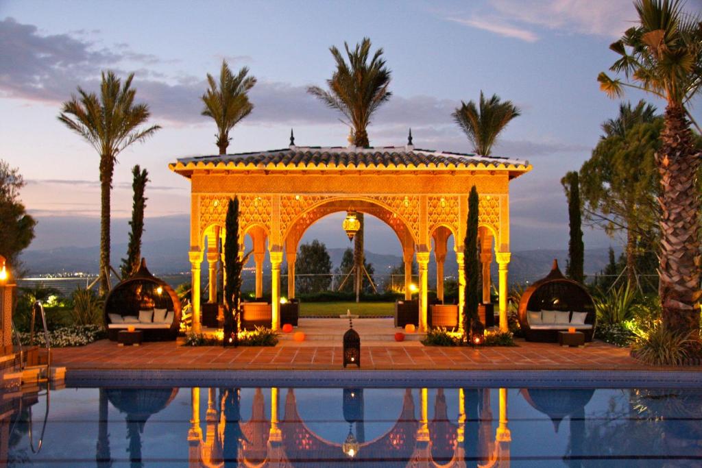 une piscine en face d'un bâtiment avec des palmiers dans l'établissement Hotel El Mirador, à Alhaurín el Grande