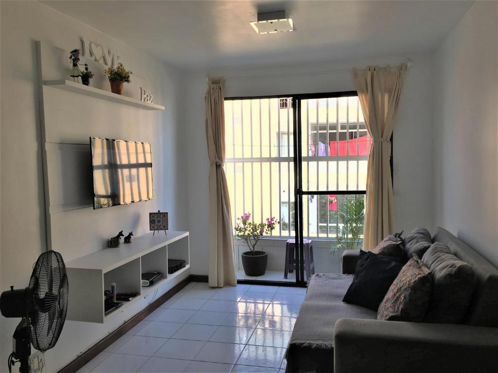 ein Wohnzimmer mit einem Sofa und einem großen Fenster in der Unterkunft Charme Barra Mar in São Luís