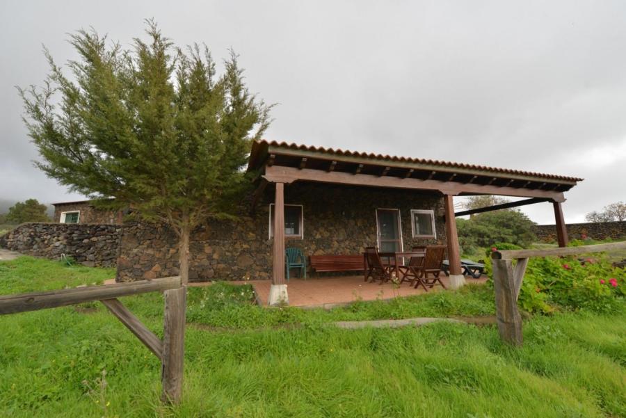 uma casa de pedra com um alpendre e uma cerca de madeira em Casa Rural El Pajar em El Pinar del Hierro