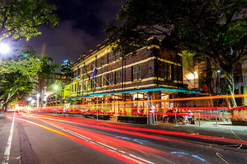 een straat in de stad 's nachts met lichtstrepen bij Mercantile Hotel in Sydney