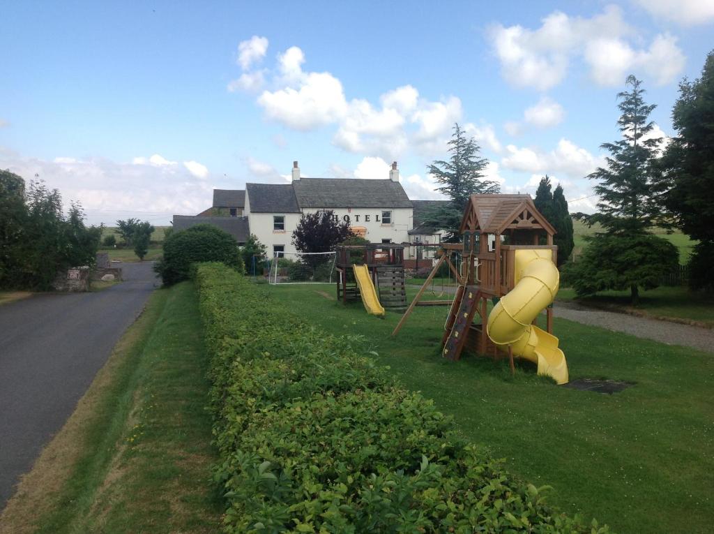 a yard with a playground with a slide and a house at Wheyrigg Hall Hotel in Wheyrigg