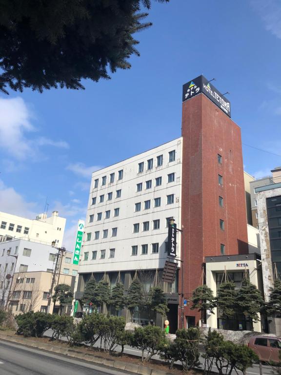 a hotel building with a sign on top of it at Hotel Tetora Asahikawa Station in Asahikawa