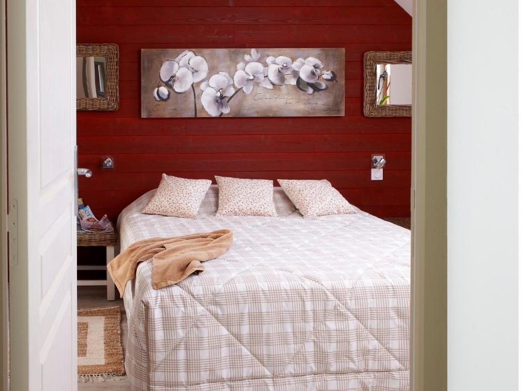 a bedroom with a bed with a red wall at Domaine Le Puits De Jeanne in Plouégat-Moysan