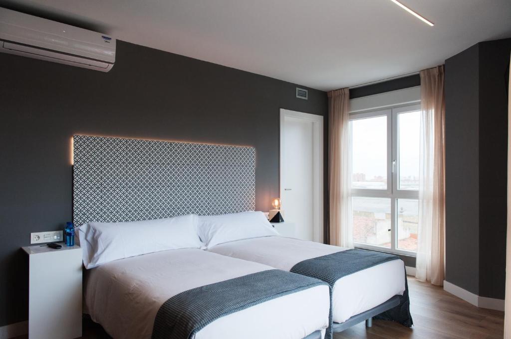 um quarto com uma cama e uma grande janela em Rener Hotel Los Campones em Gijón