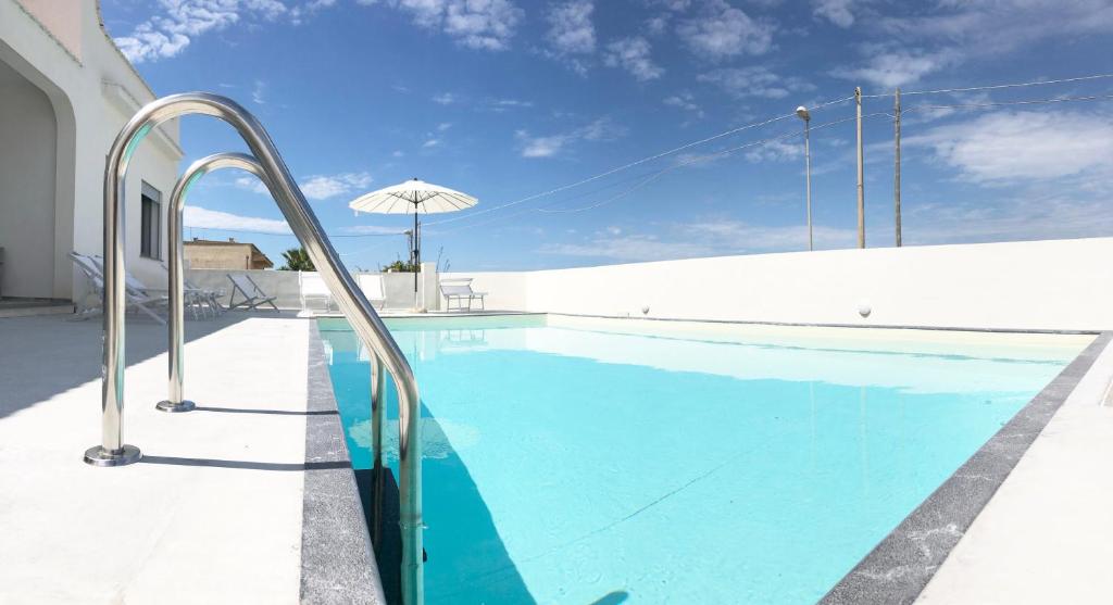 una piscina blu con un muro bianco e un ombrellone di Casa Vacanza Gemini a Marsala
