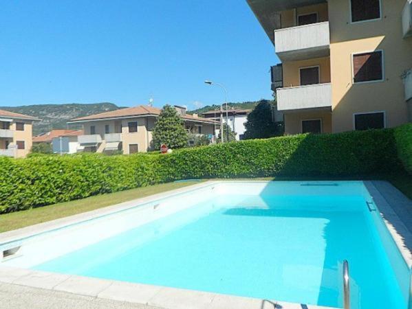 een groot blauw zwembad voor een gebouw bij Welcome Traveller LA PERLA APARTMENTS in Garda