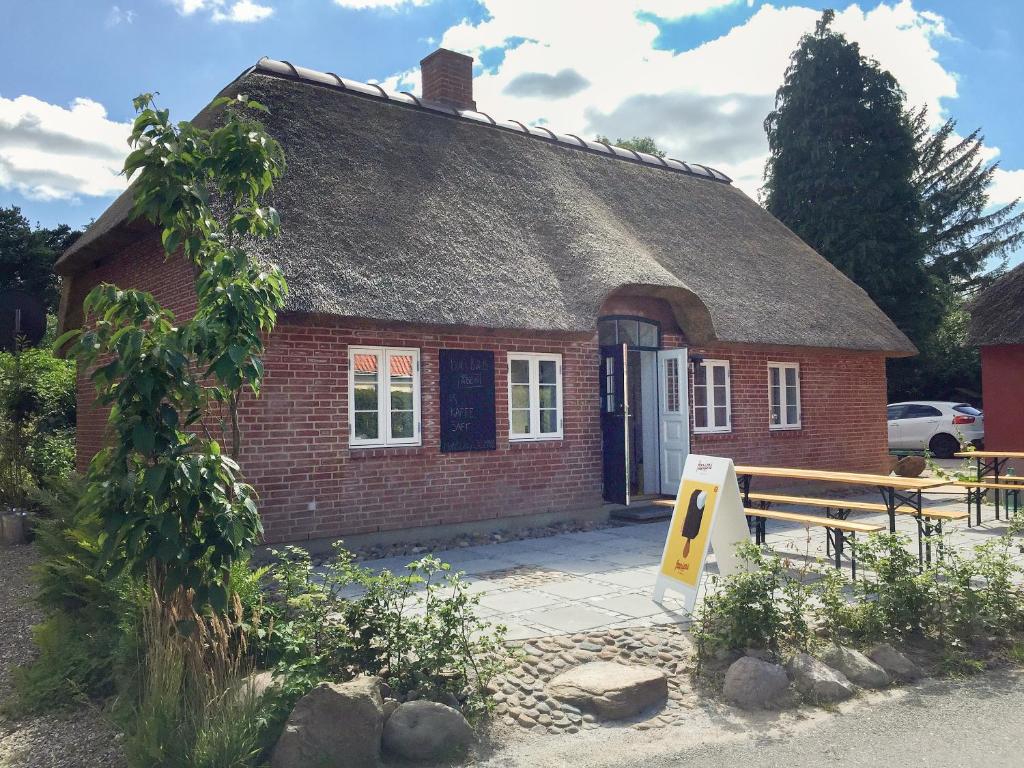 een klein bakstenen huis met een rieten dak bij Boes Bed & Breakfast in Skanderborg