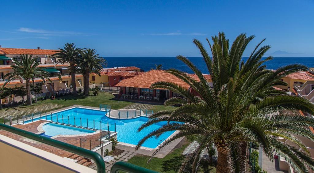 un complejo con una piscina y una palmera en AstroSunrise, en Los Cancajos