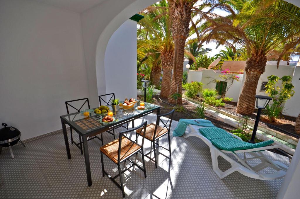 a table and chairs on a patio with palm trees at Ferienwohnung PRESIDENTE - Pool - Glasfaserinternet - Costa Calma in Costa Calma