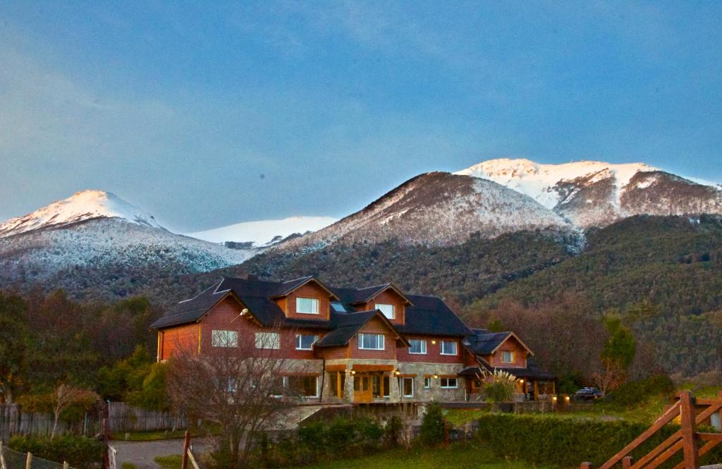 a house in the mountains with snow covered mountains at Alma Andina Hosteria in Villa La Angostura